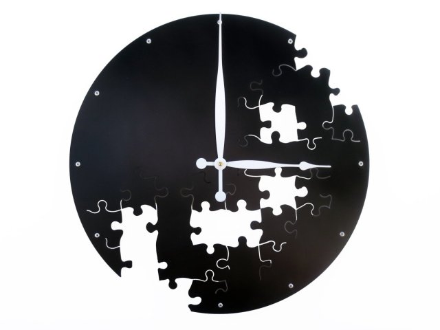 A photo of black clock on a white background with puzzle piece-shaped cutouts randomly placed over the lower three quarters of the clock